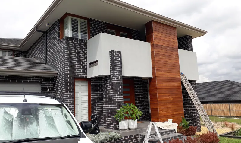Exterior repaint in progress — ladders set up at a two-storey brick and timber-clad home — Parramatta